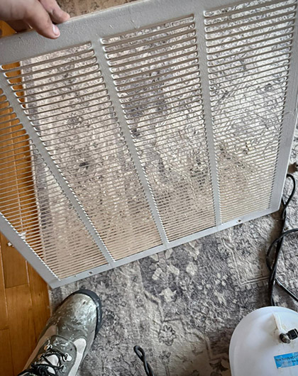 Dirty HVAC return vent cover being removed for inspection